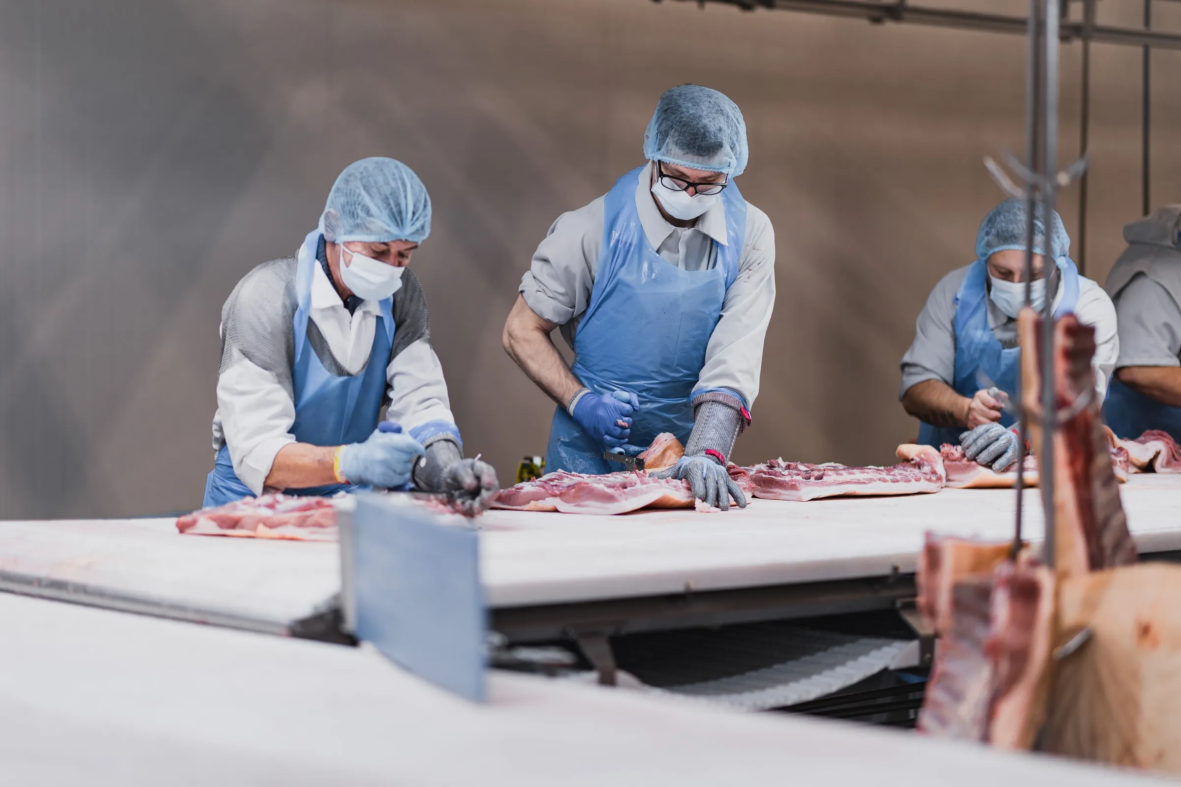 Drie versnijders ontbenen deelstukken aan de snijtafel