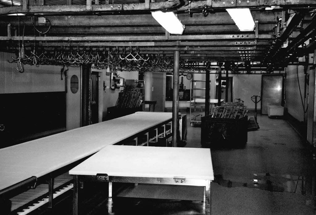 Zwart-witfoto van de vroegere snijzaal van De Stoop met lege snijtafels